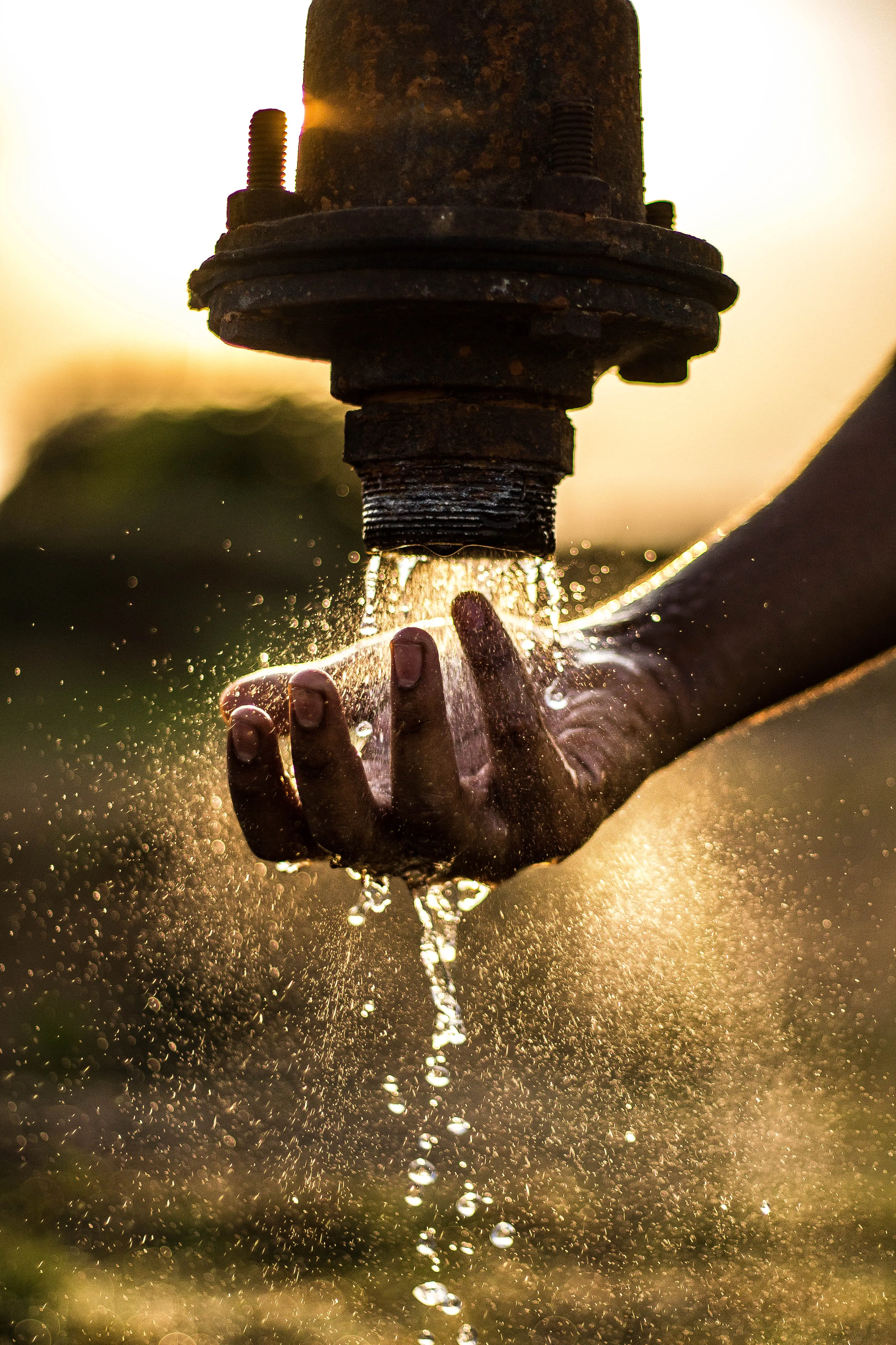 A close-up of a hand underneath a running outdoor tap