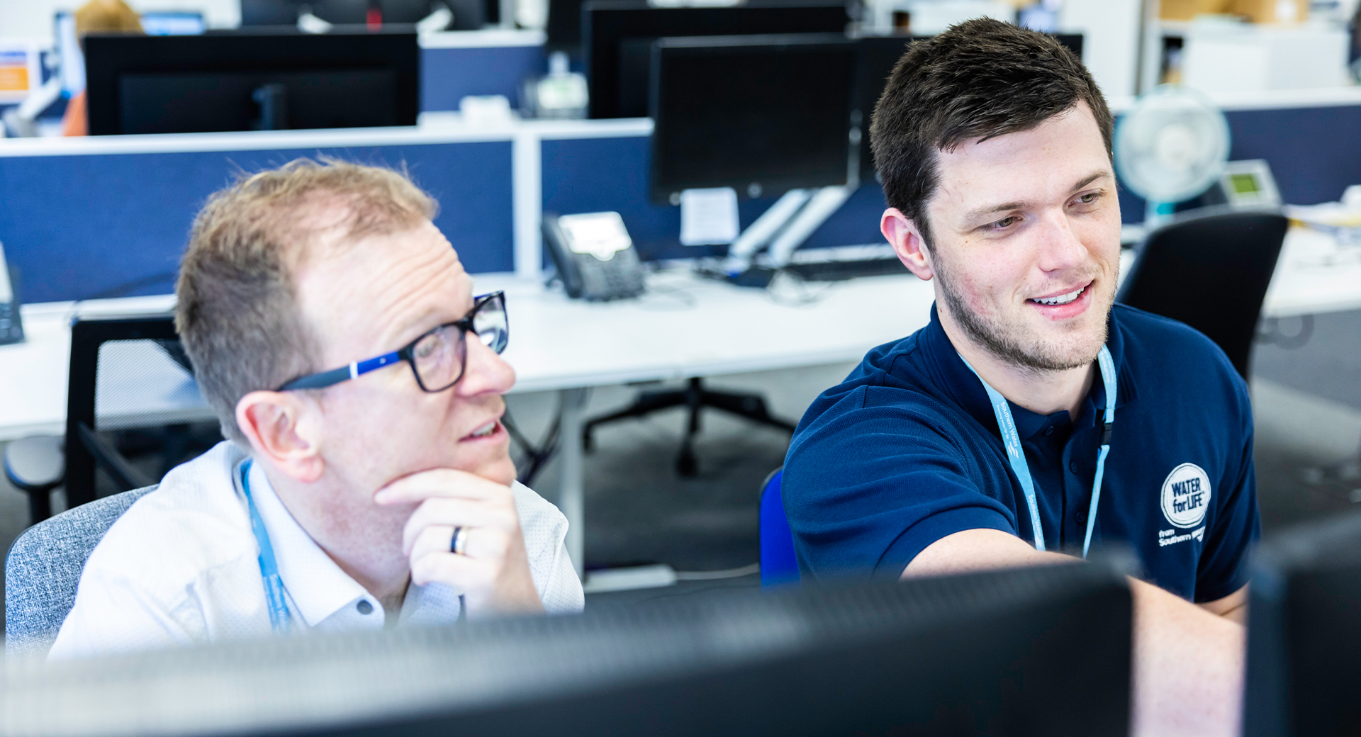 Two Southern Water employees sit in an office and look at a computer screen